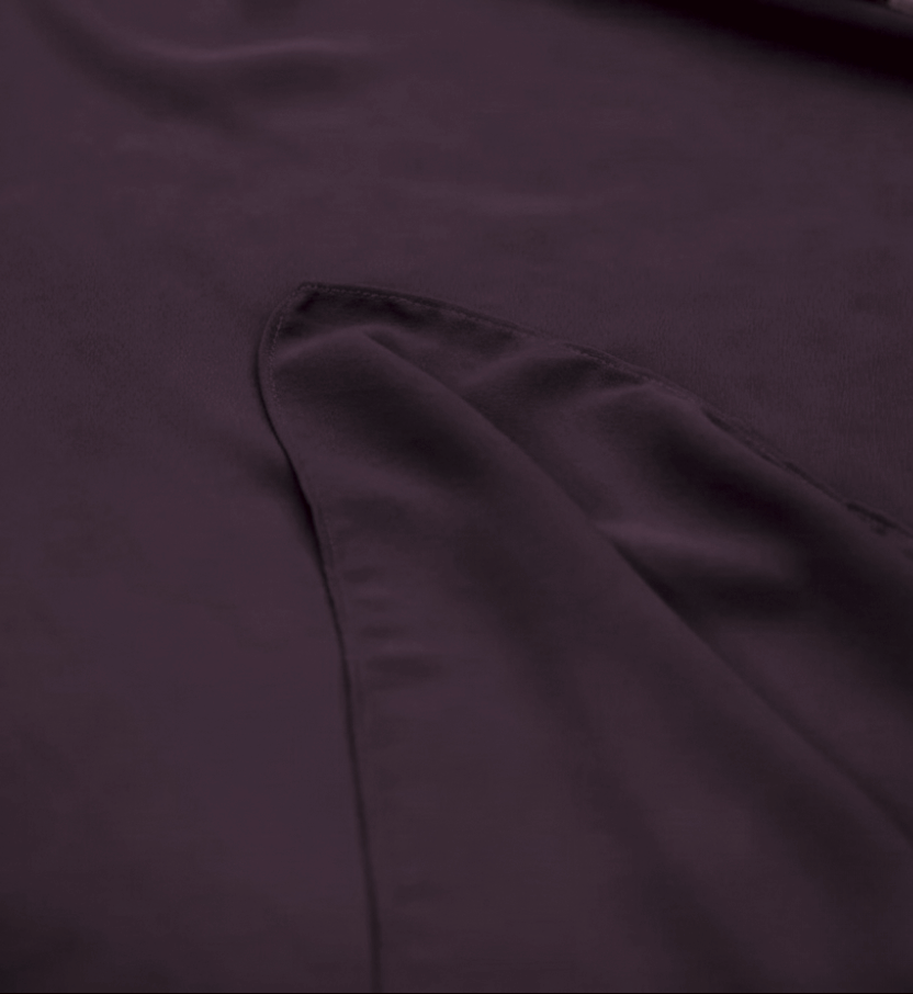 Close-up of a dark plum purple fabric surface with a folded section showing the material texture and stitching.