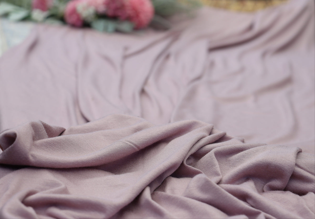 Purple blanket draped over a surface with flowers in the background