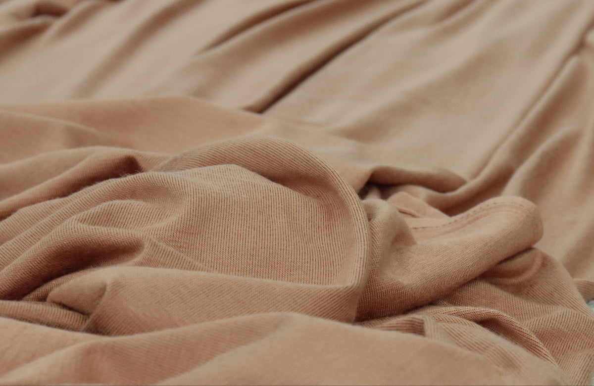A draped piece of soft brown fabric, laid out on a light-colored surface.