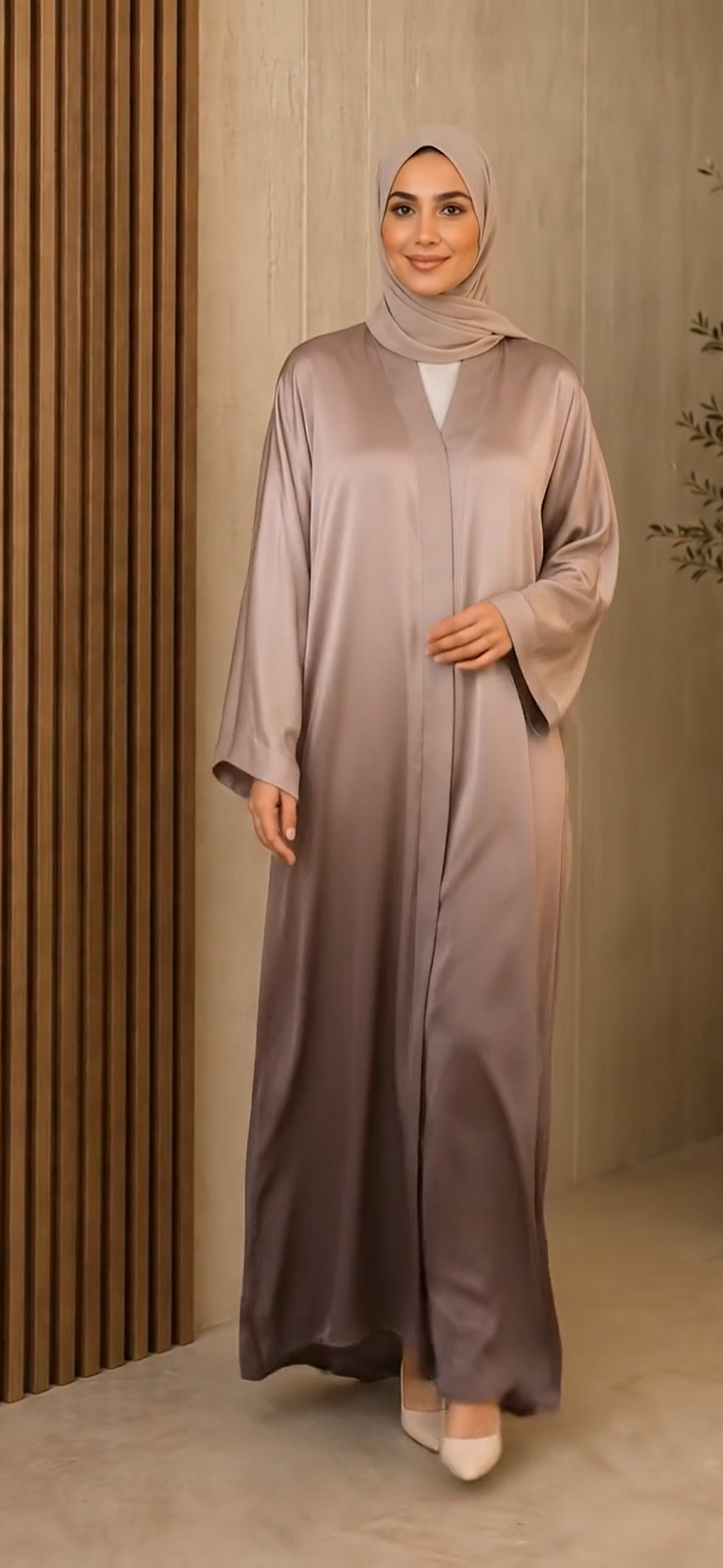 A woman wearing a long, flowing abaya in a dusty mauve-purple color with a matching hijab, standing in front of a modern wooden slatted wall.