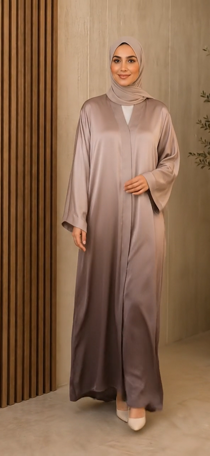 A woman wearing a long, flowing abaya in a dusty mauve-purple color with a matching hijab, standing in front of a modern wooden slatted wall.
