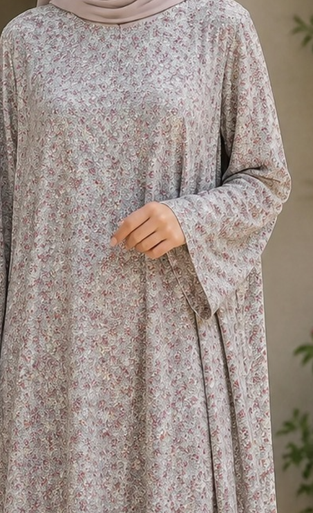 A woman wearing a long-sleeved, loose-fitting abaya dress with a delicate beige and brown floral pattern, paired with a matching hijab.