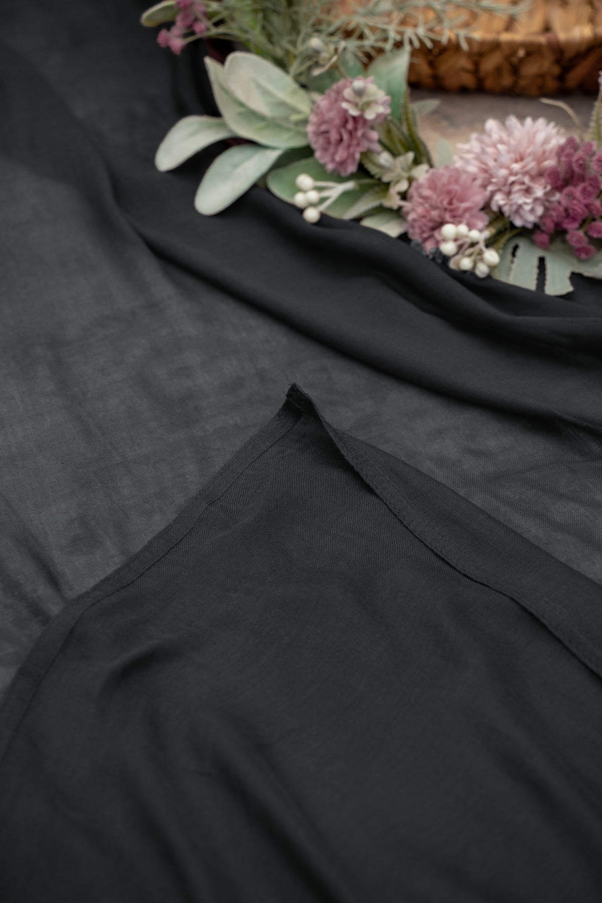 Black fabric with a floral arrangement on a textured surface.