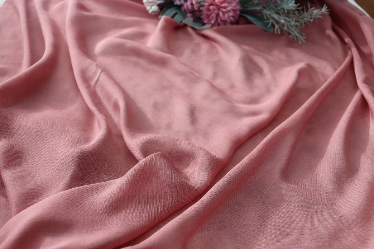 Pink fabric with a floral arrangement on a textured surface