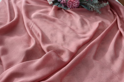Pink fabric with a floral arrangement on a textured surface
