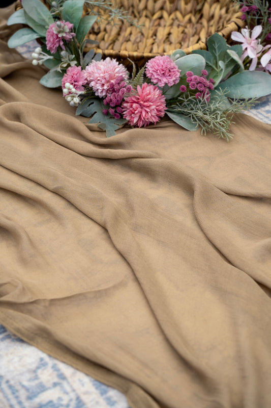 Pink flowers and green leaves on a brown fabric surface