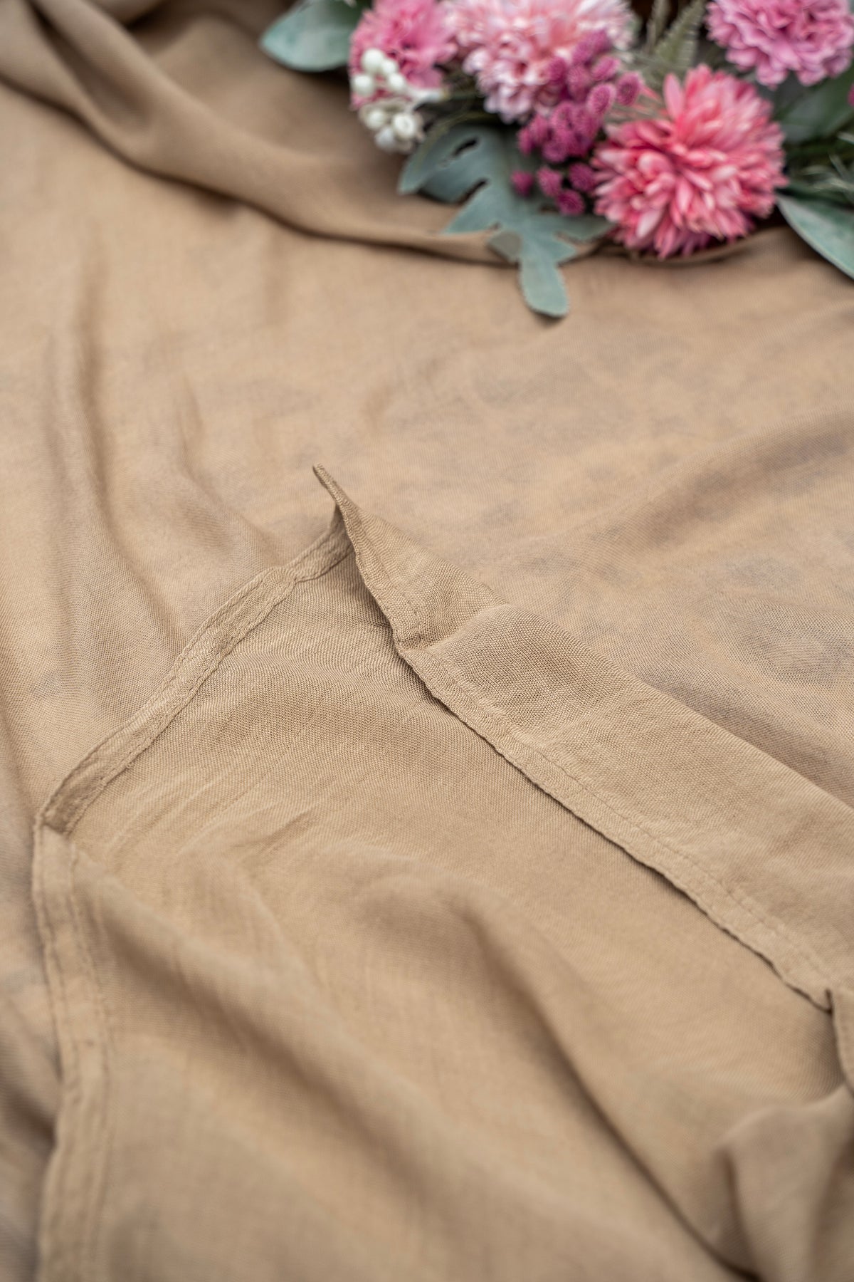 Close-up of beige fabric with a floral arrangement in the background