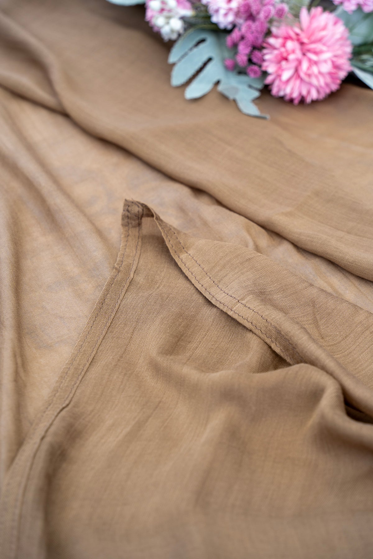 Brown fabric with a floral arrangement in the background
