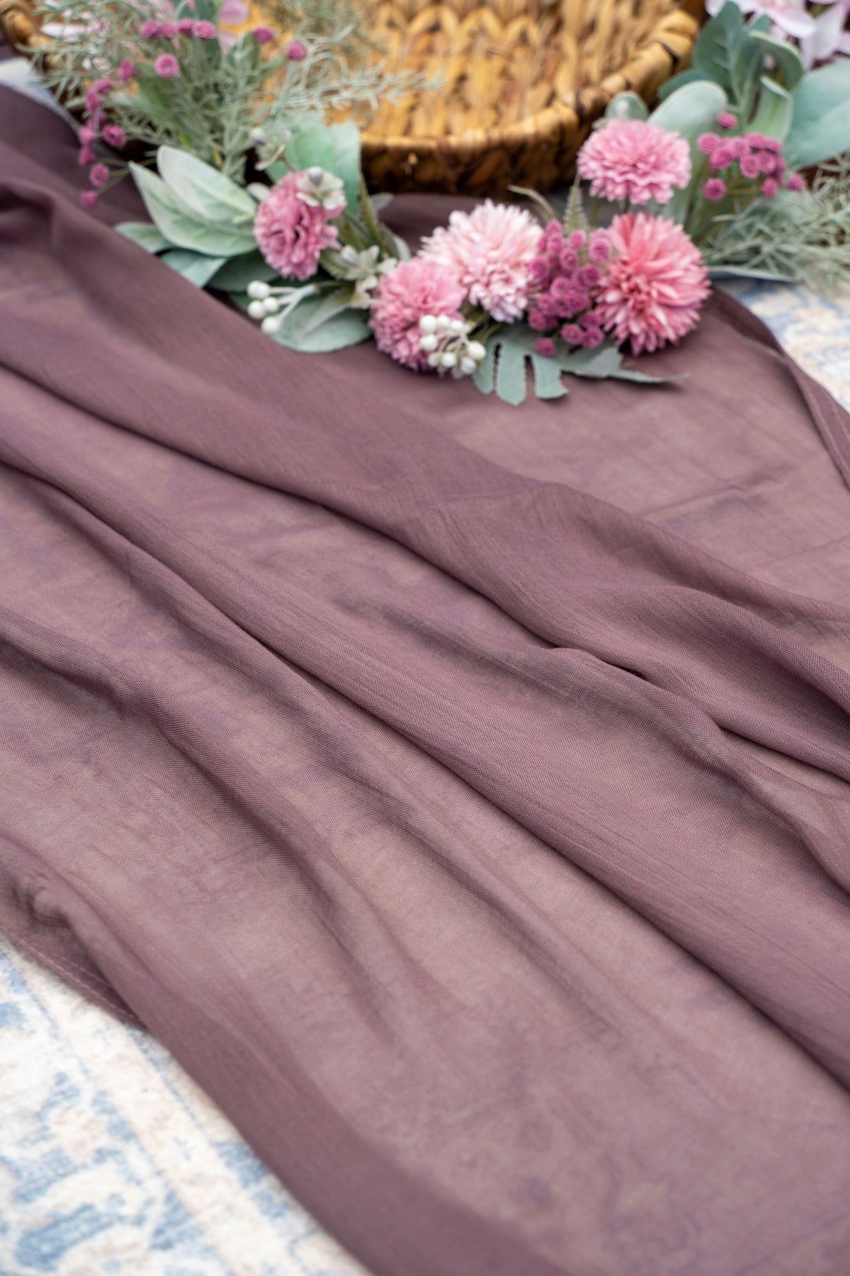 Brown fabric with pink flowers and green leaves on a textured surface