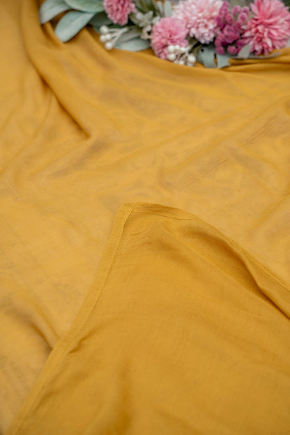 Mustard yellow fabric with a floral arrangement in the background