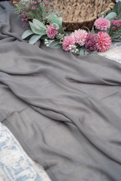 Gray fabric with pink flowers and green leaves on a textured surface