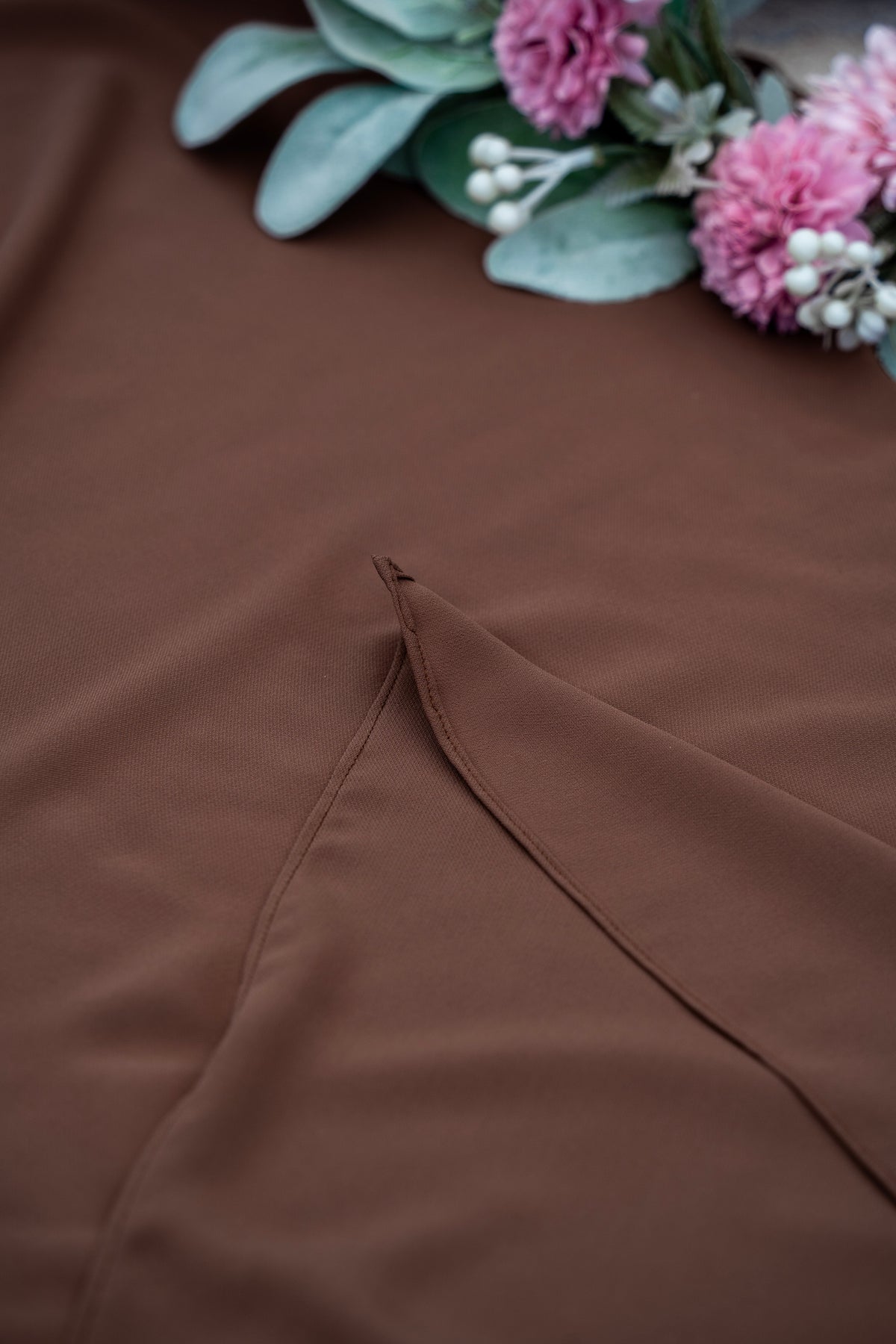 Brown fabric with a floral arrangement on a brown surface