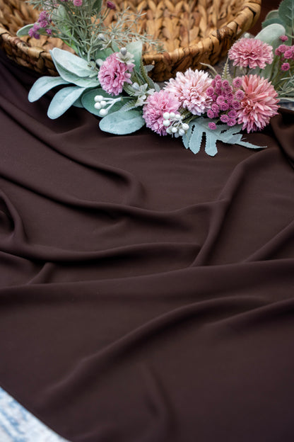 Floral arrangement on a brown fabric surface with a woven basket in the background