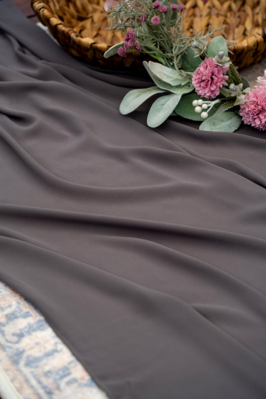 Dark gray fabric with a woven basket and floral arrangement on a textured surface