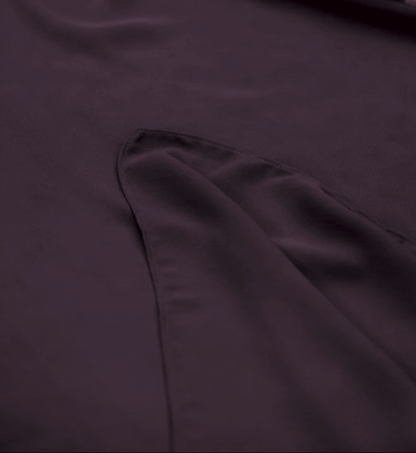 Close-up of a dark plum purple fabric surface with a folded section showing the material texture and stitching.