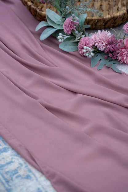 Pink fabric with flowers and a woven basket on a textured surface