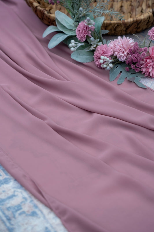 Pink fabric with flowers and a woven basket on a textured surface
