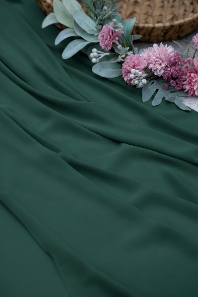 Dark green fabric with pink flowers and greenery on a textured surface