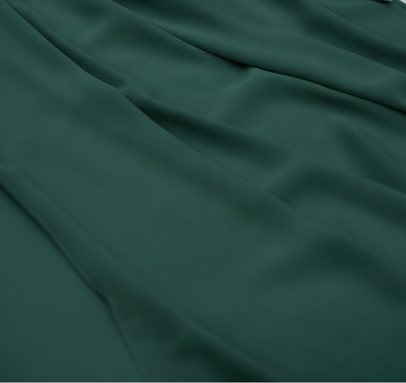 Dark green fabric with pink flowers and greenery on a textured surface
