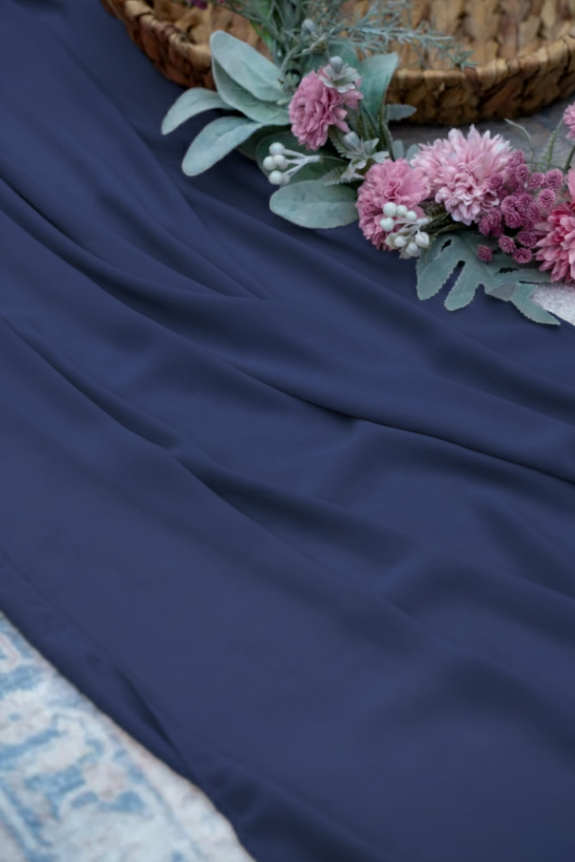 Navy blue fabric with pink flowers and green leaves on a textured surface