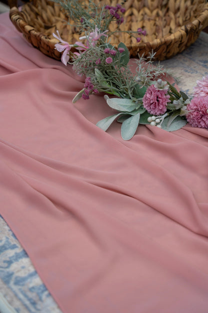 Pink fabric with a floral arrangement on a textured surface