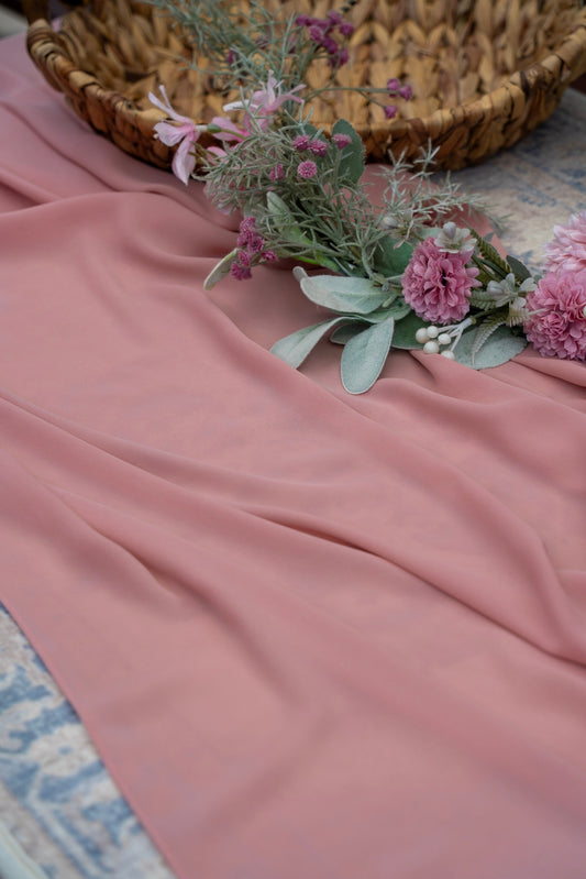 Pink fabric with a floral arrangement on a textured surface