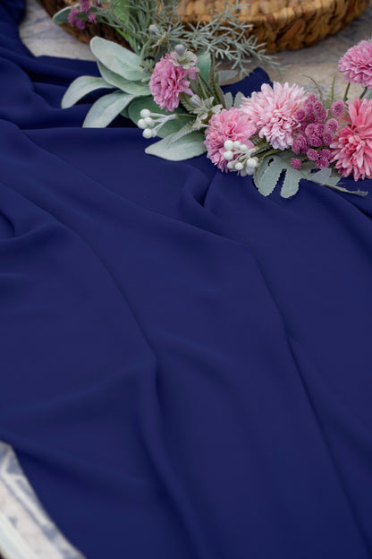Navy blue fabric with pink flowers and greenery on a textured surface