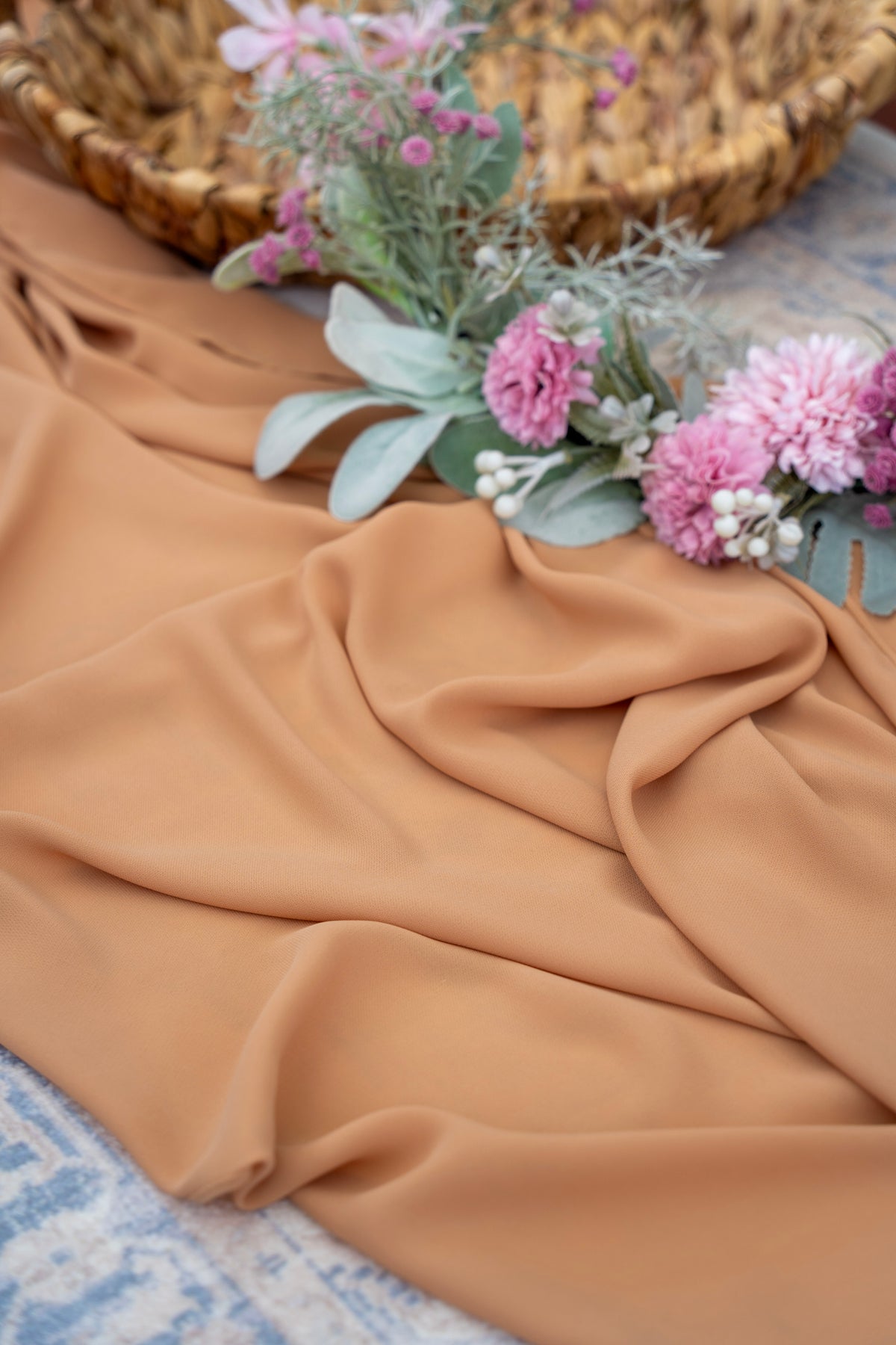 Brown fabric with pink flowers and green leaves on a textured surface