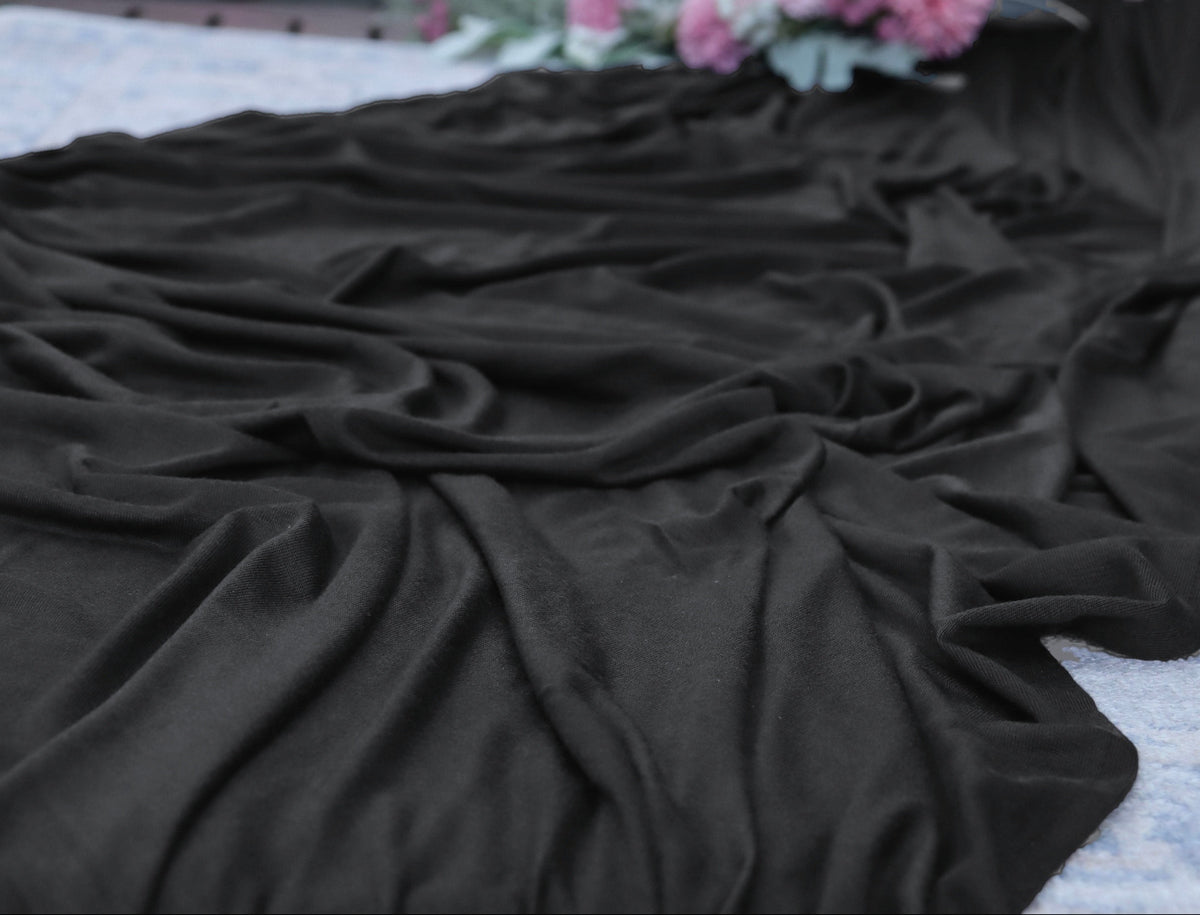 Black fabric on a textured surface with flowers in the background