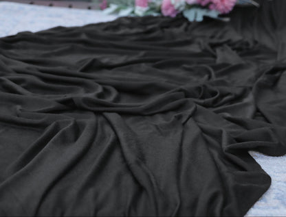 Black fabric on a textured surface with flowers in the background