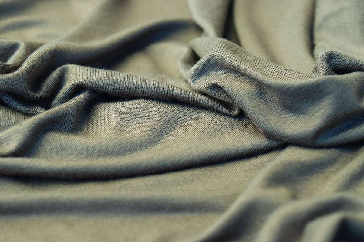 Close-up of draped fabric with a soft, textured weave in a muted sage green color.