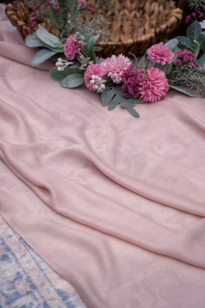 Pink fabric with pink flowers and greenery on a textured surface