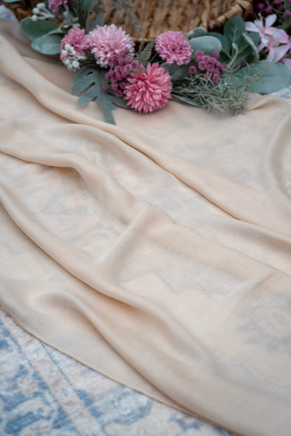 Beige fabric with pink flowers and greenery on a textured surface