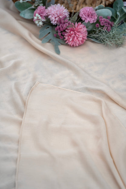 Close-up of a beige fabric with pink flowers and green leaves on a light background