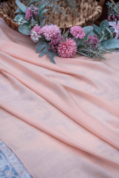 Pink fabric with pink flowers and green leaves on a textured surface