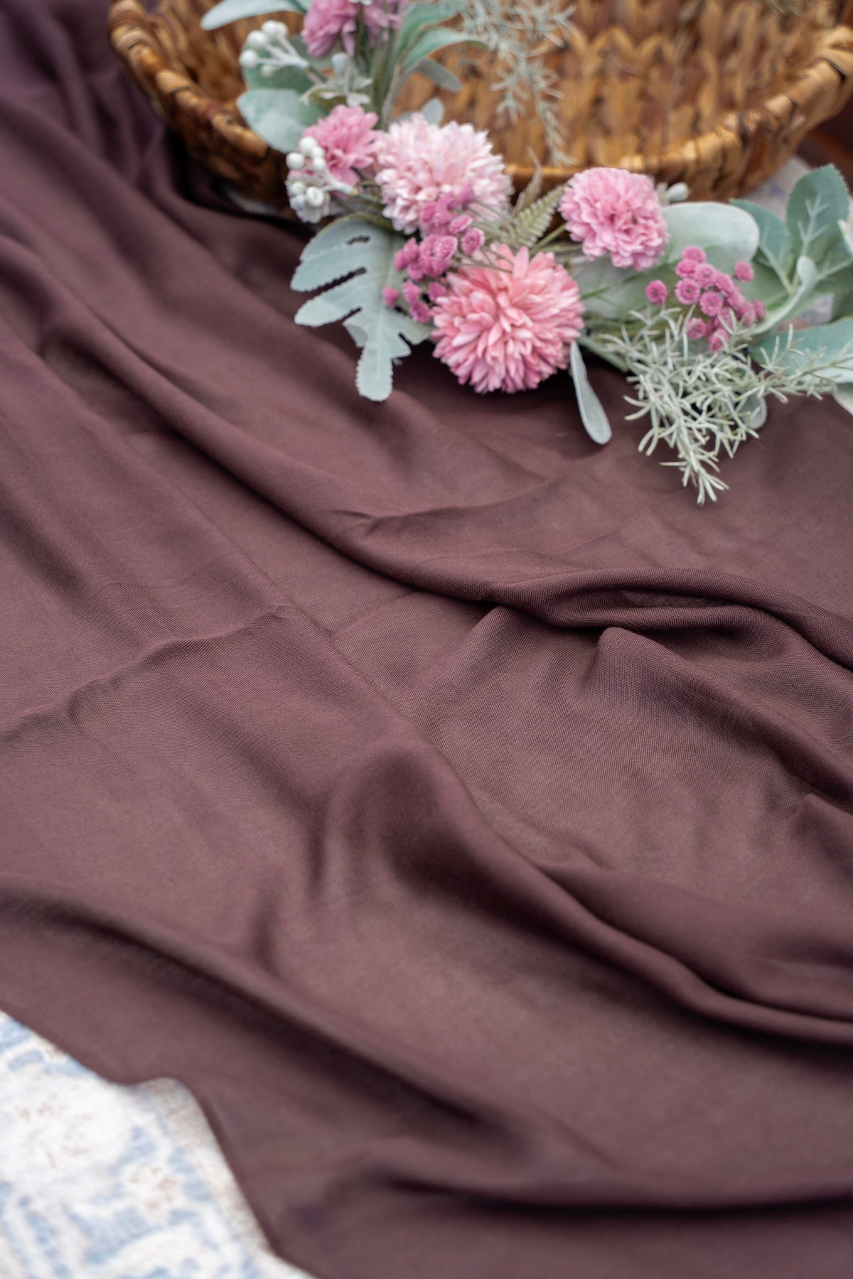 Pink flowers and green leaves on a brown fabric surface