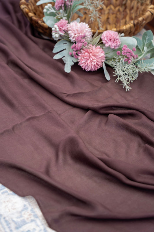 Pink flowers and green leaves on a brown fabric surface