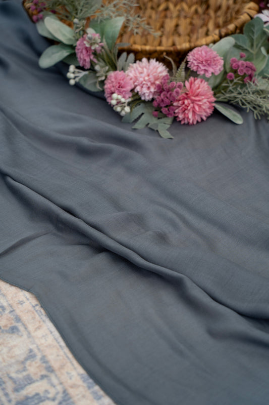 Gray fabric with pink flowers and greenery on a textured surface