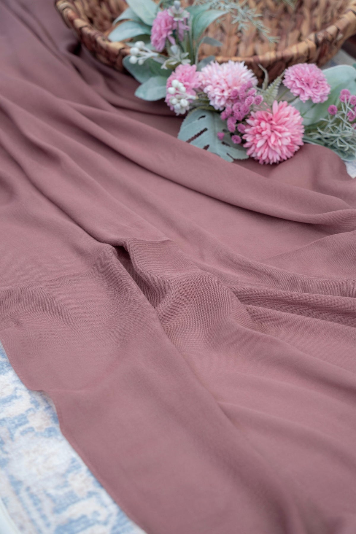 Mauve fabric with pink flowers and a woven basket in the background