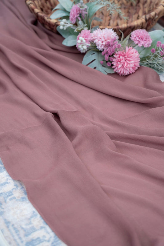 Mauve fabric with pink flowers and a woven basket in the background