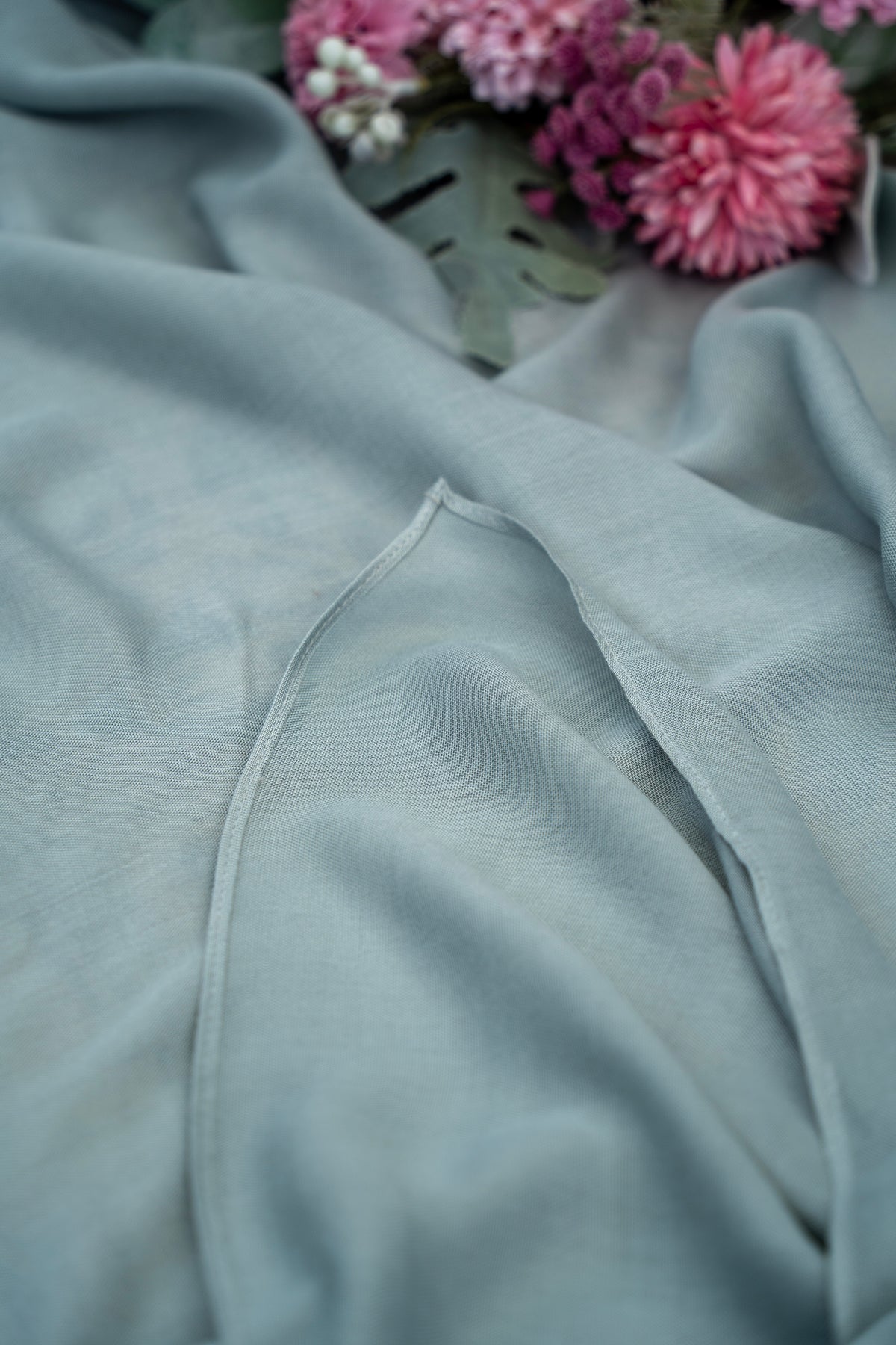 Gray fabric with a zipper and pink flowers in the background