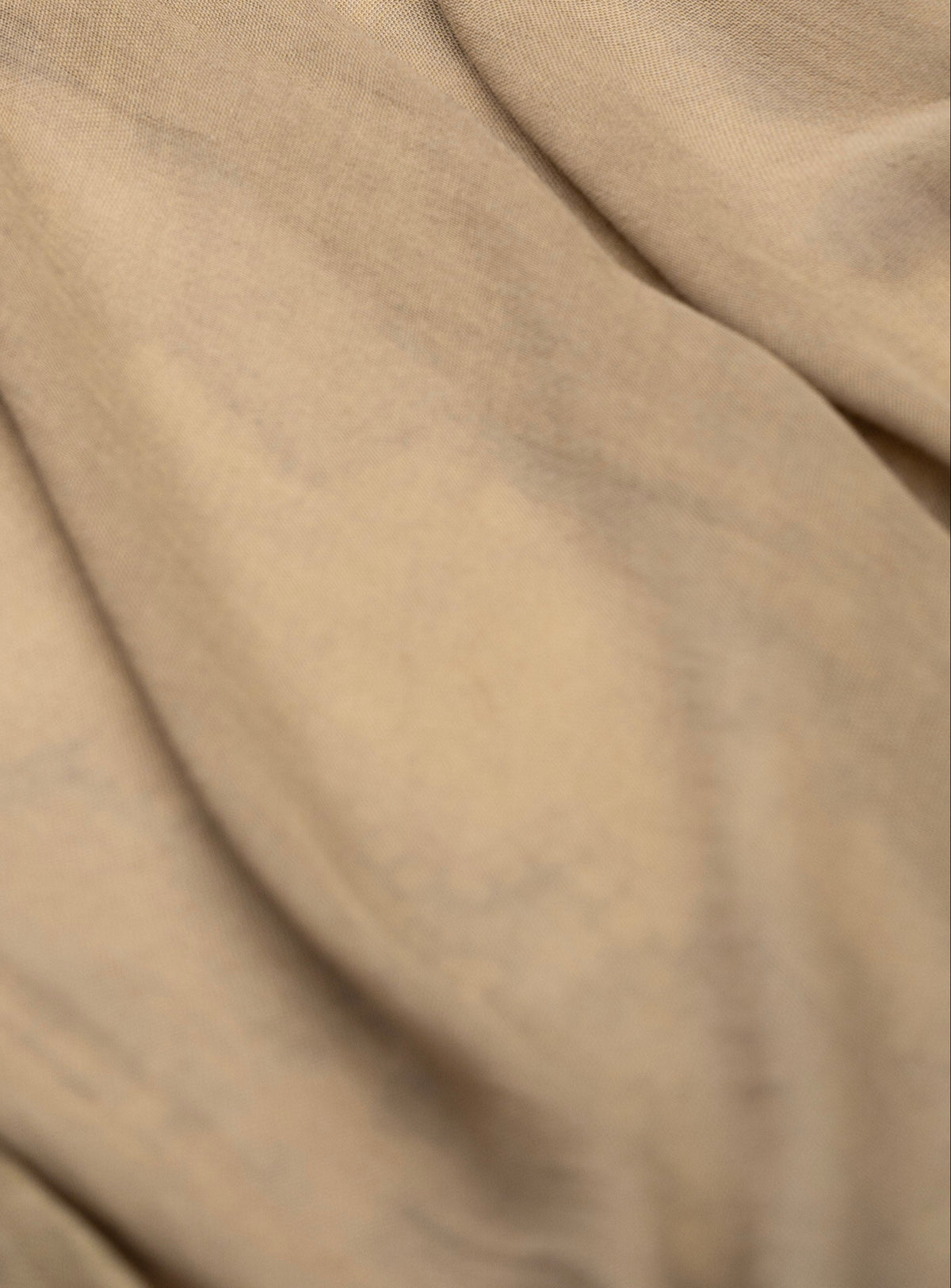 A close-up of draped beige fabric with soft folds and a smooth texture.