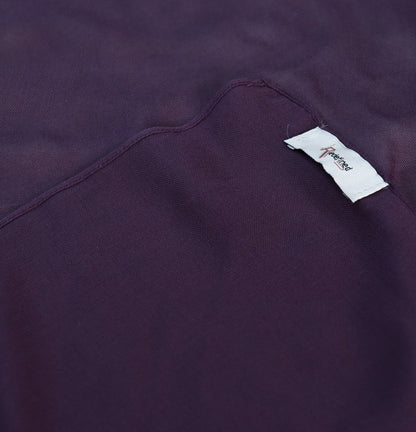 A close-up of draped dark plum purple fabric with soft folds
