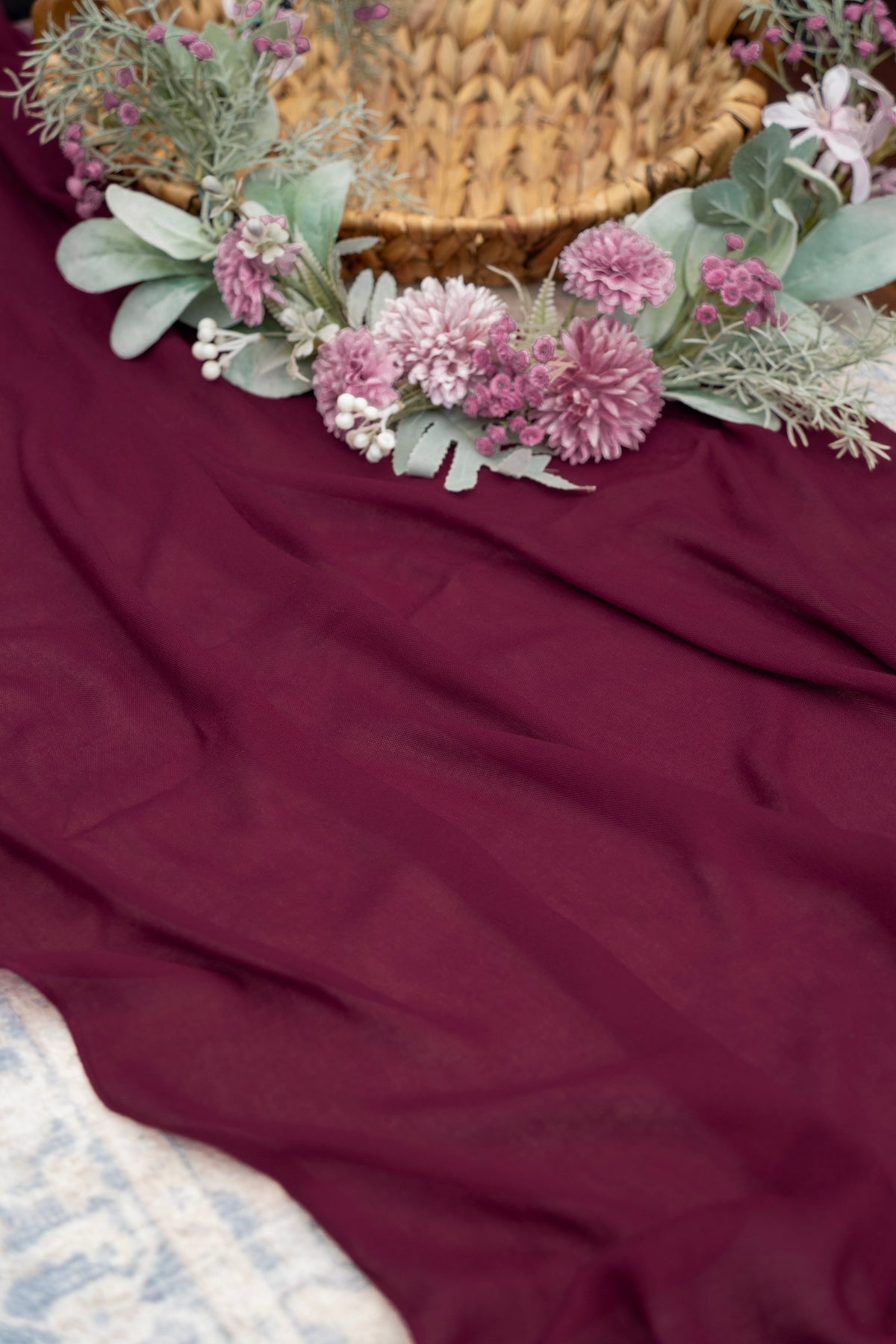 Floral wreath with pink flowers and green leaves on a red fabric background