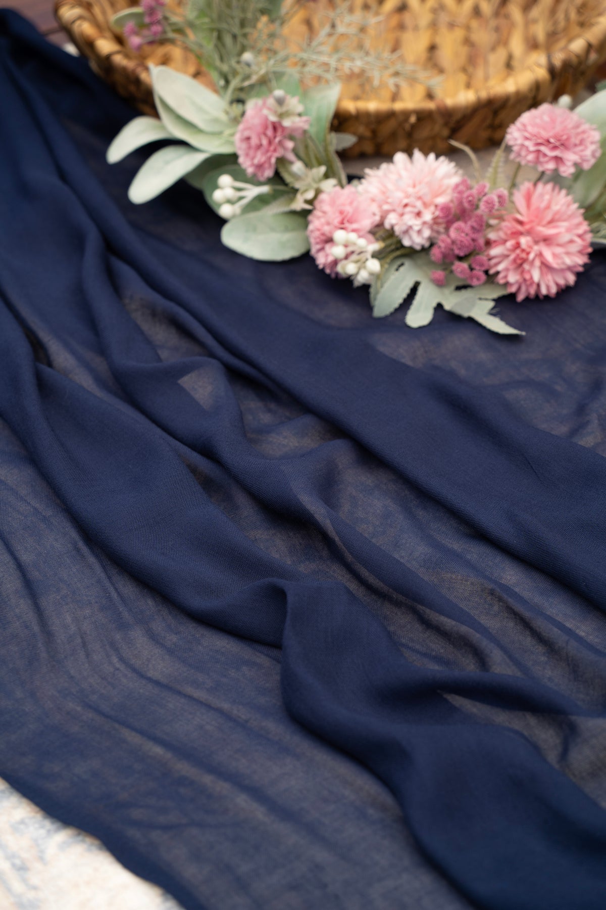 Navy blue fabric with pink flowers and greenery on a textured surface