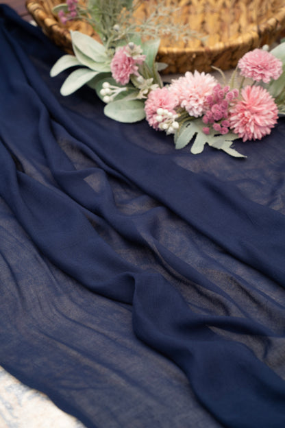 Navy blue fabric with pink flowers and greenery on a textured surface