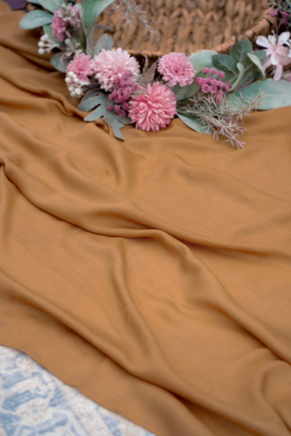 Brown fabric with pink flowers and green leaves on a textured surface