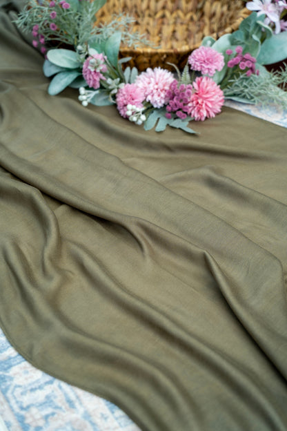 Green fabric with pink flowers and greenery on a textured surface