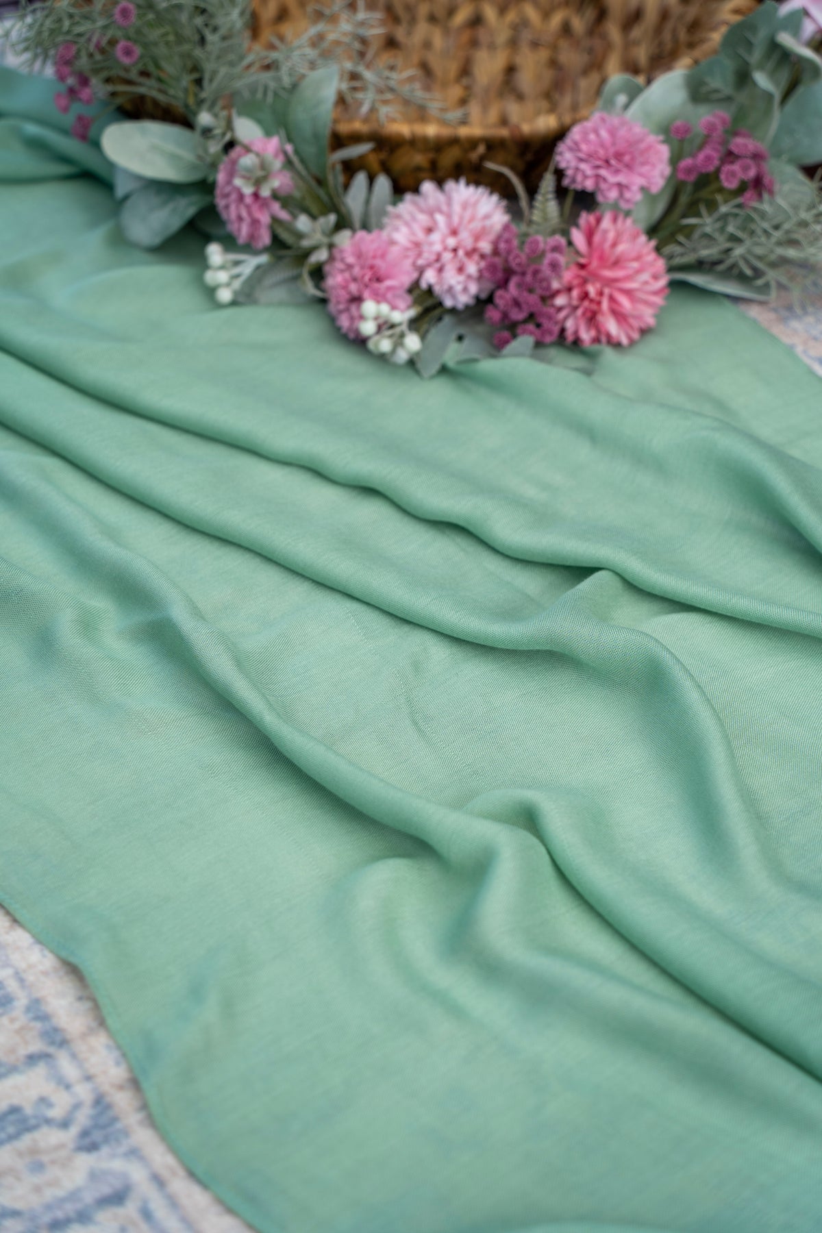 Mint green fabric with pink flowers and a woven basket in the background