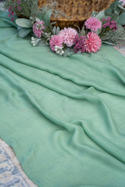 Mint green fabric with pink flowers and a woven basket in the background